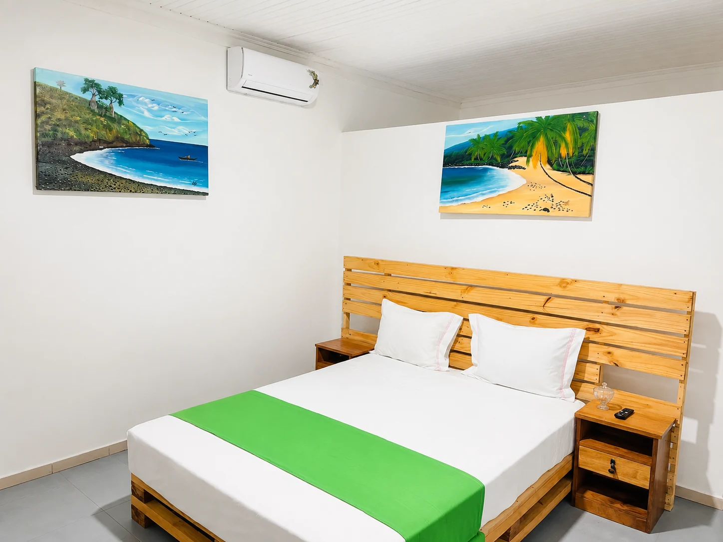 Quarto claro com cama de casal e pinturas tropicais